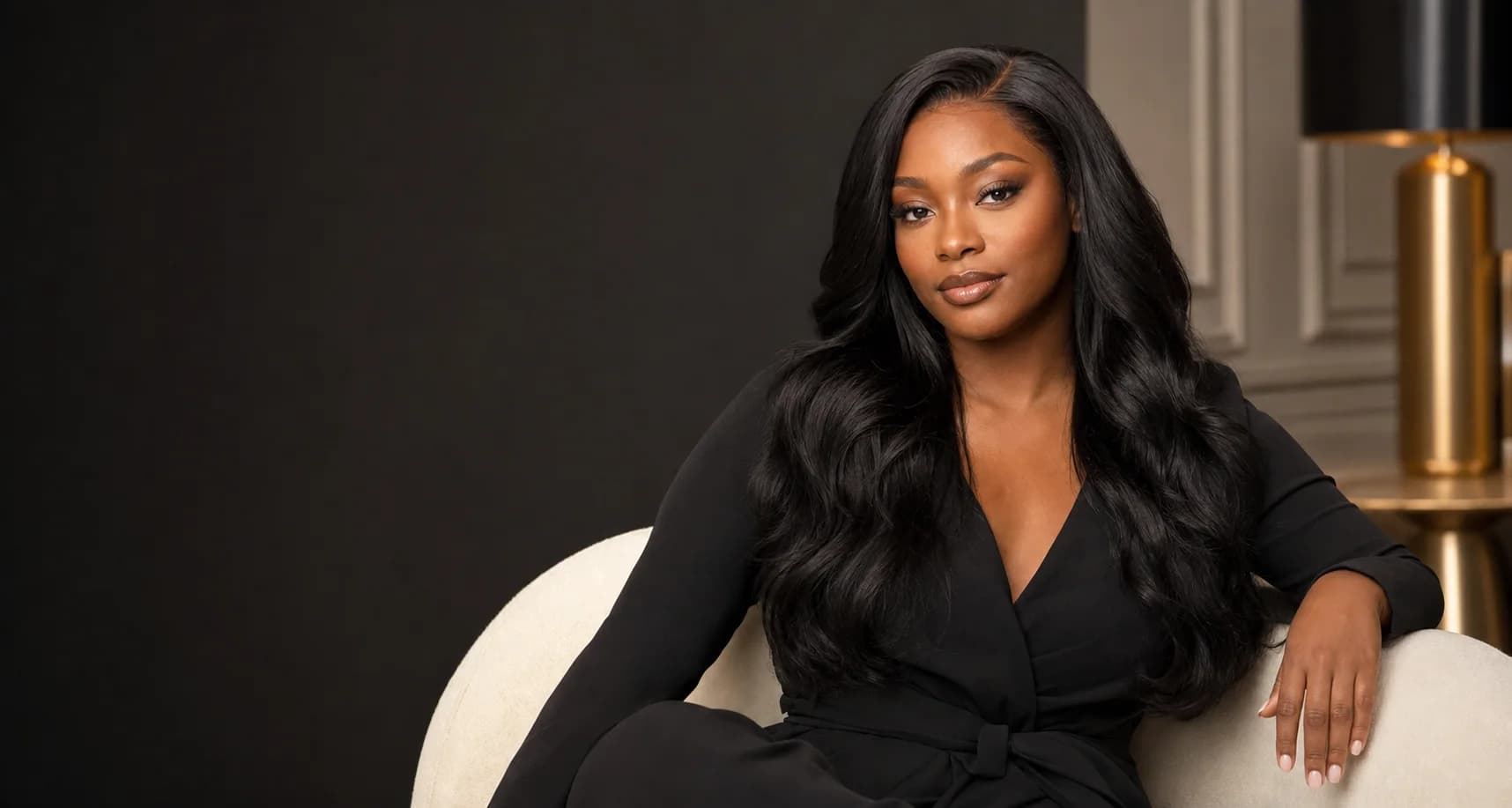 Confident woman wearing a long black body-wave wig in an elegant studio